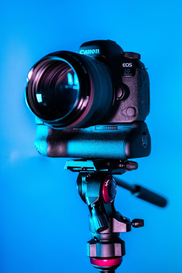 Close-up of a DSLR camera on a tripod with a blue background.