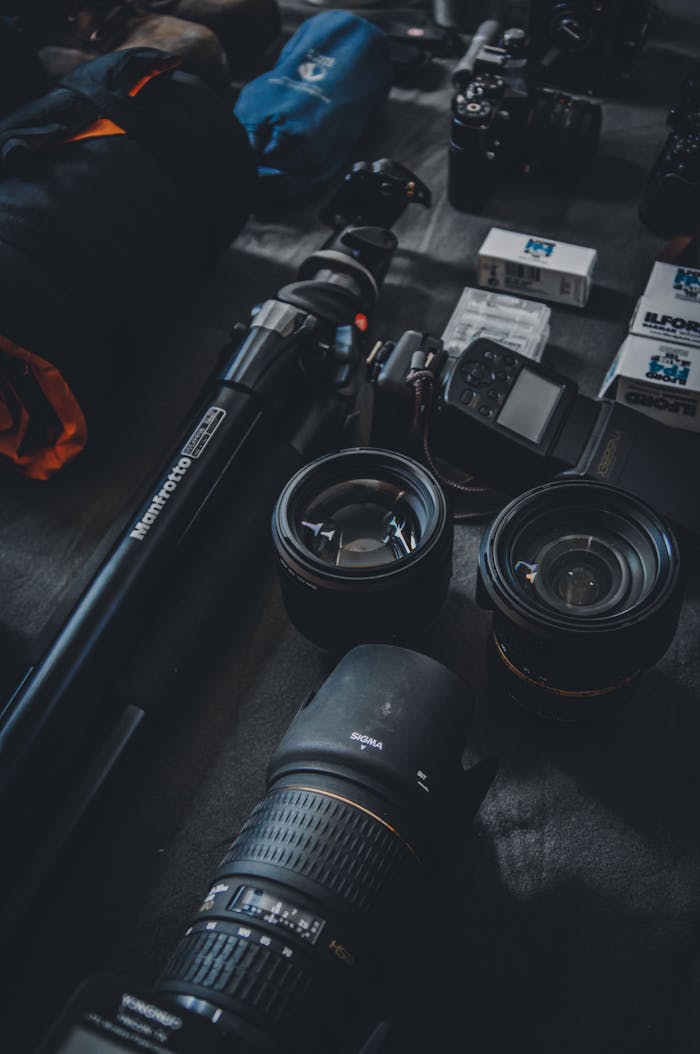 Close-up of a photography setup featuring camera lenses, tripod, and film rolls for professional use.